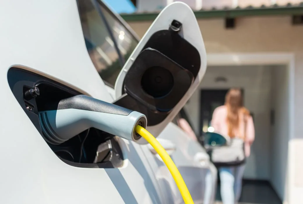 Type 2 charging cable plugged into the charging port of a white electric car on a driveway at home